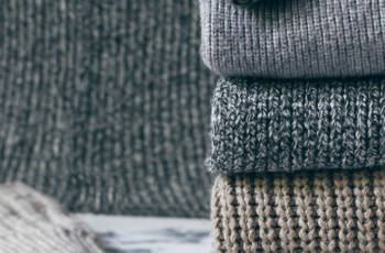 stack of cozy knitted sweaters on wooden background. Autumn-wint